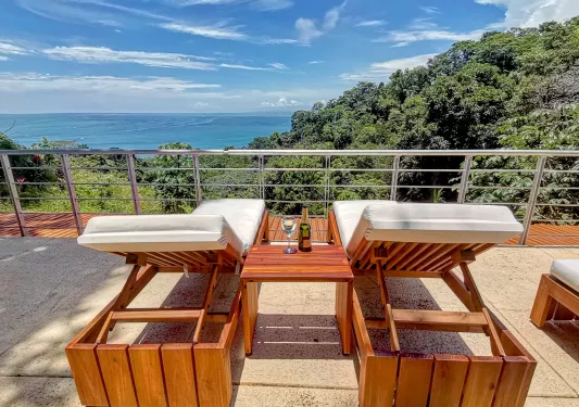 two lounge chairs on a deck overlooking the water