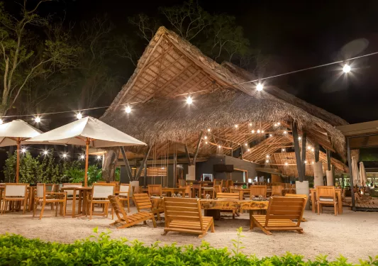 Outdoor hut with wooden chairs and tables on the sand