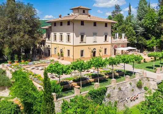 Yellow and white building with an outdoor courtyard, surrounded by trees and reclining chairs
