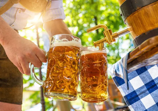 Person filling two mugs with beer