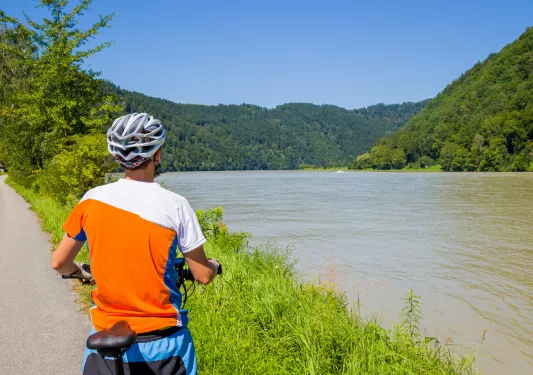 Man riding a bike while looking out to a lake and large grassy hills