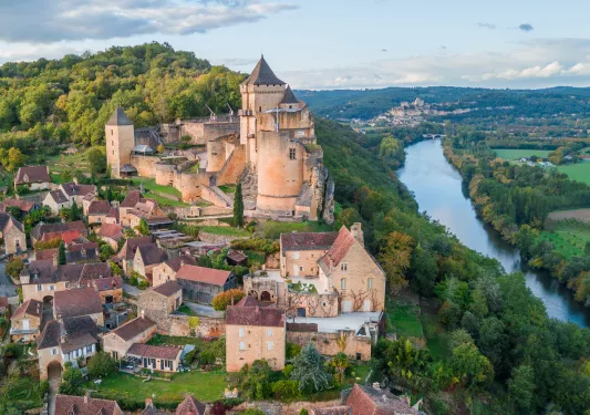 stone buildings surrounded by trees along a river