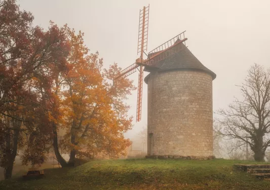 stone windmill building with tree on the left