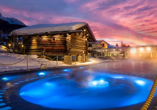 Northern lights shine over a small lodge and hot tub