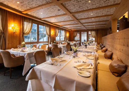 Indoor dining area with cushioned benches and cloths over each table