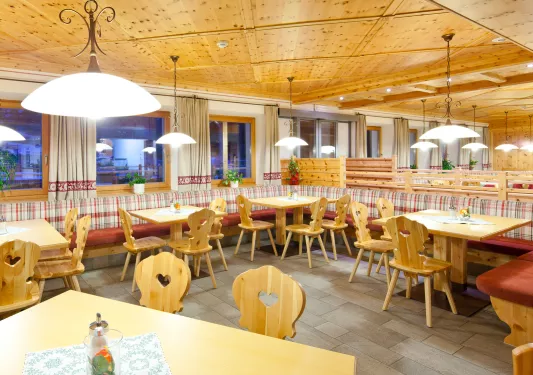 Dining area with wooden chairs and tables with windows along the walls