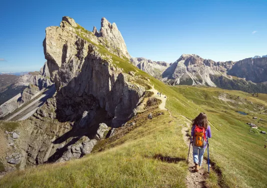 Woman hiking on a dirt trail towards the edge of a cliff