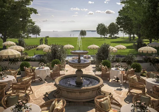 Outdoor dining area around a fountain, surrounded by a large area of grass
