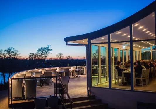 Restaurant with large open windows and outdoor seating on a balcony