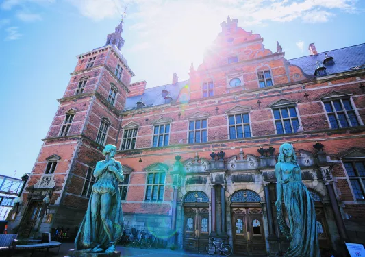 Rustic, red brick building with two blue statues outside