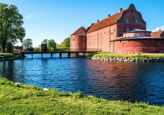 Red brick building with a bridge surrounded by water
