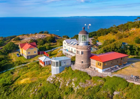 Lighthouse building with smaller buildings and the ocean in the distance