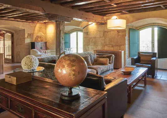 Indoor lounge with large, wooden pillars and wooden furniture, with a globe on the coffee table
