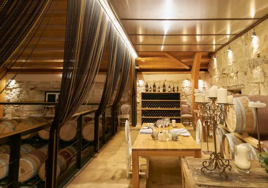 Underground cellar full of wine barrels and a table with two chairs