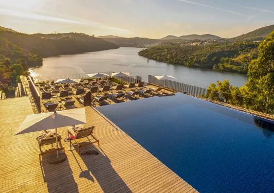 hotel pool with lounge chairs and a view of water