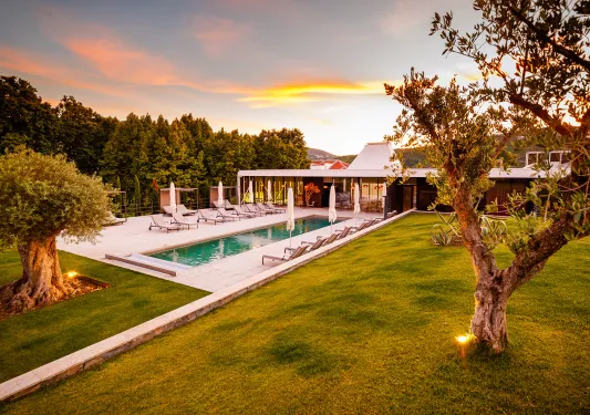 hotel pool surrounded by lounge chairs at sunset