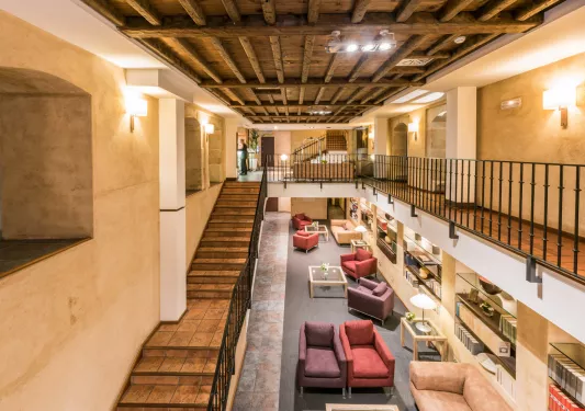 Indoor library with cushioned chairs and a stairway on the left