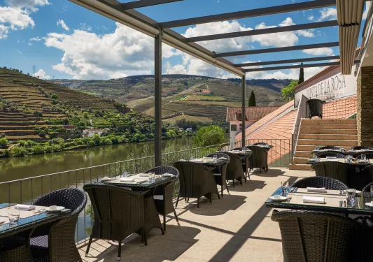Outdoor dining area along a river with black chairs and tables