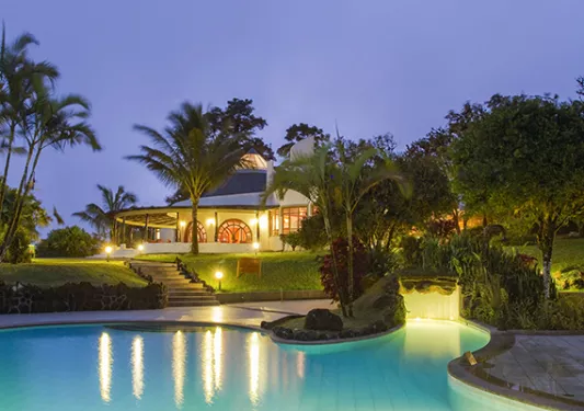 swimming pool lit up at night next to hotel