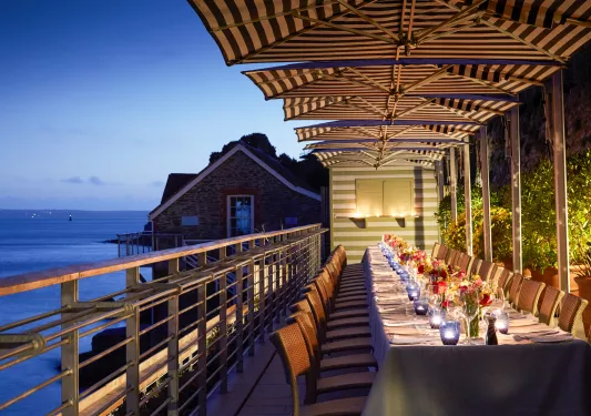 Large balcony with a long dining table with flowers and wine glasses