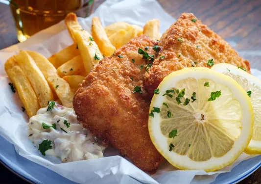 A plate of fish and chips with two slices of lemon