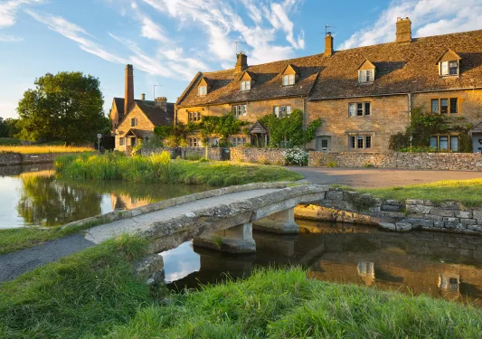 Narrow, stone bridge leading to a rustic building