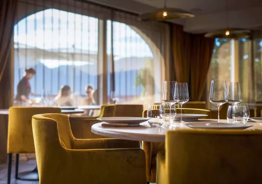 Indoor dining area with yellow cushioned chairs and wine glasses on the tables