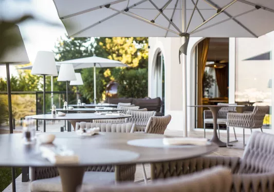 Outdoor eating area with tan cushioned chairs and umbrellas