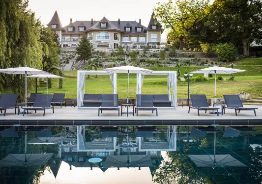 Outdoor pool with umbrellas with a castle-like building in the background