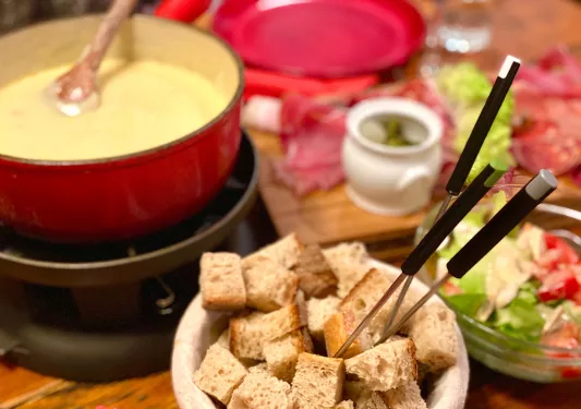 A small bowl of bread next to a pot of cheese fondue