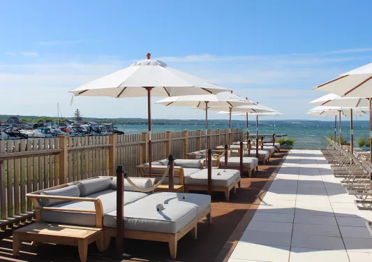 Gray, cushioned beds with umbrellas next to the ocean