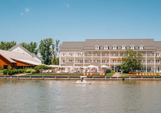 Outdoor view of large, white building with balconies looking out to a boat in the ocean