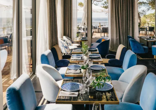 Indoor dining area with white and blue cushioned seating and large curtains