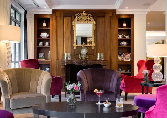 Indoor lounge with purple and gray cushioned chairs in front of a fireplace