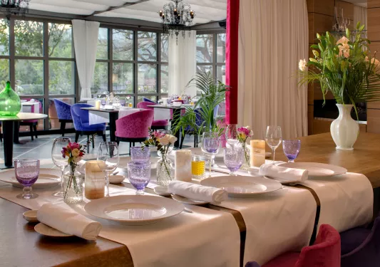Dining area with pink and blue cushioned chairs and purple glasses on the table