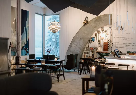 Indoor lounge with black tables and chairs with candles on each table