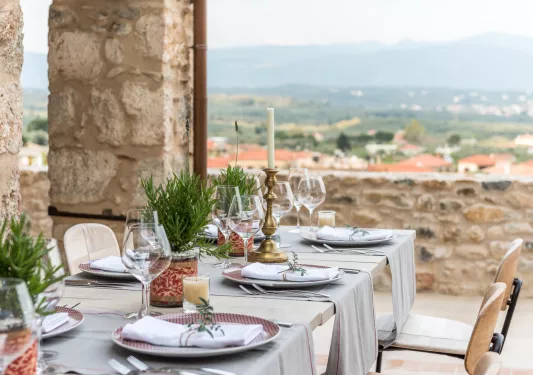 Outdoor dining table with wine glasses, overlooking a small town