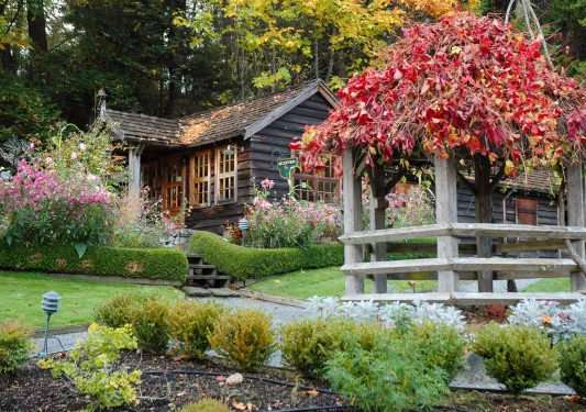Wooden cottage surrounded by flowers and a stone pathway