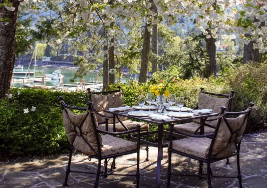 Dining table outdoors with glasses of wine and cushioned chairs