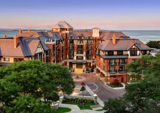 Outdoor view of red brick hotel building with a roundabout for cars outside