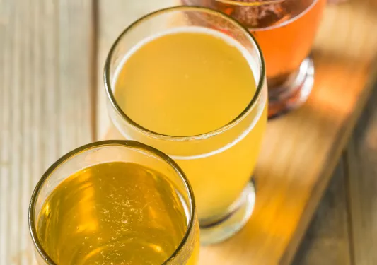 A wooden plank with different cups of beer on it