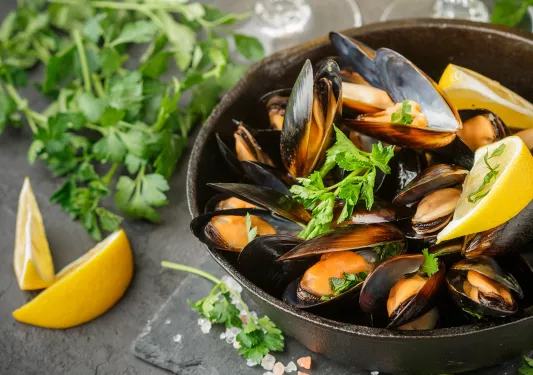 Bowel of cooked mussels with lemons and parsley