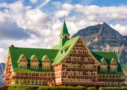 Large hotel building with a green roof, with a mountain the background