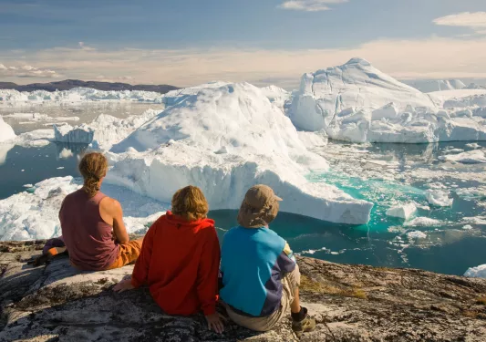 Three people look out at a sea of icebergs