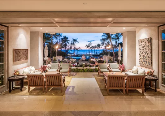 Lobby with a man playing a guitar in the background and the ocean behind him