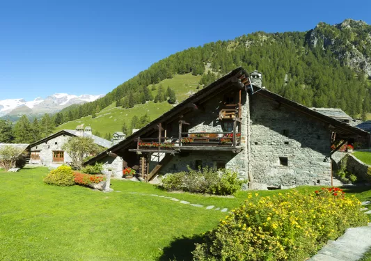 Stone building with a wooden balcony with an open grass area in front