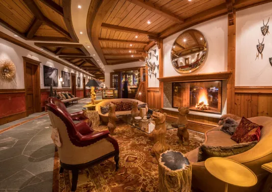 Indoor lodge lobby with wooden furniture and a fireplace