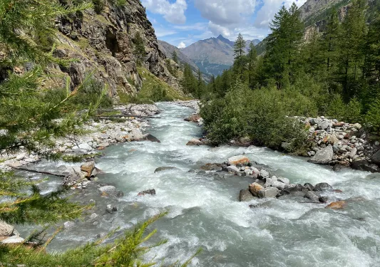 Active river filled with rocks, surrounded by two tall mountains