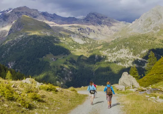 Three people descending a gravel trail on a mountain