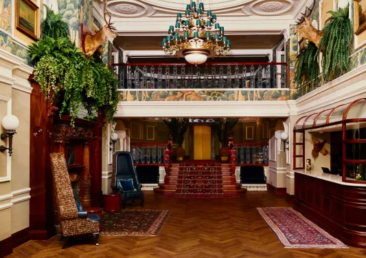 Hotel lobby with antique rugs on the floor and a small bridge walkway on the second floor